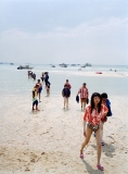 A group of Korean tourists in matching shirts wade ashore on Pattaya beach after a boat trip.